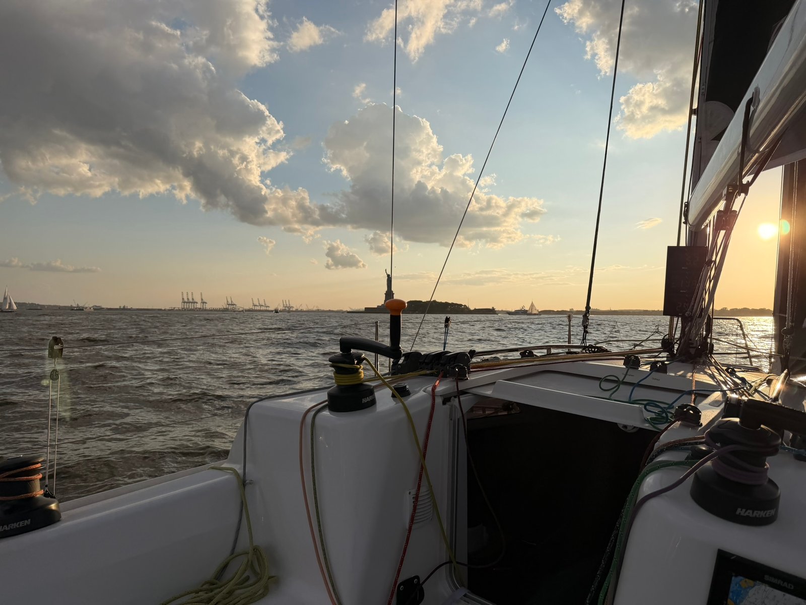 Liberty Island and port cranes — evening light across the bay